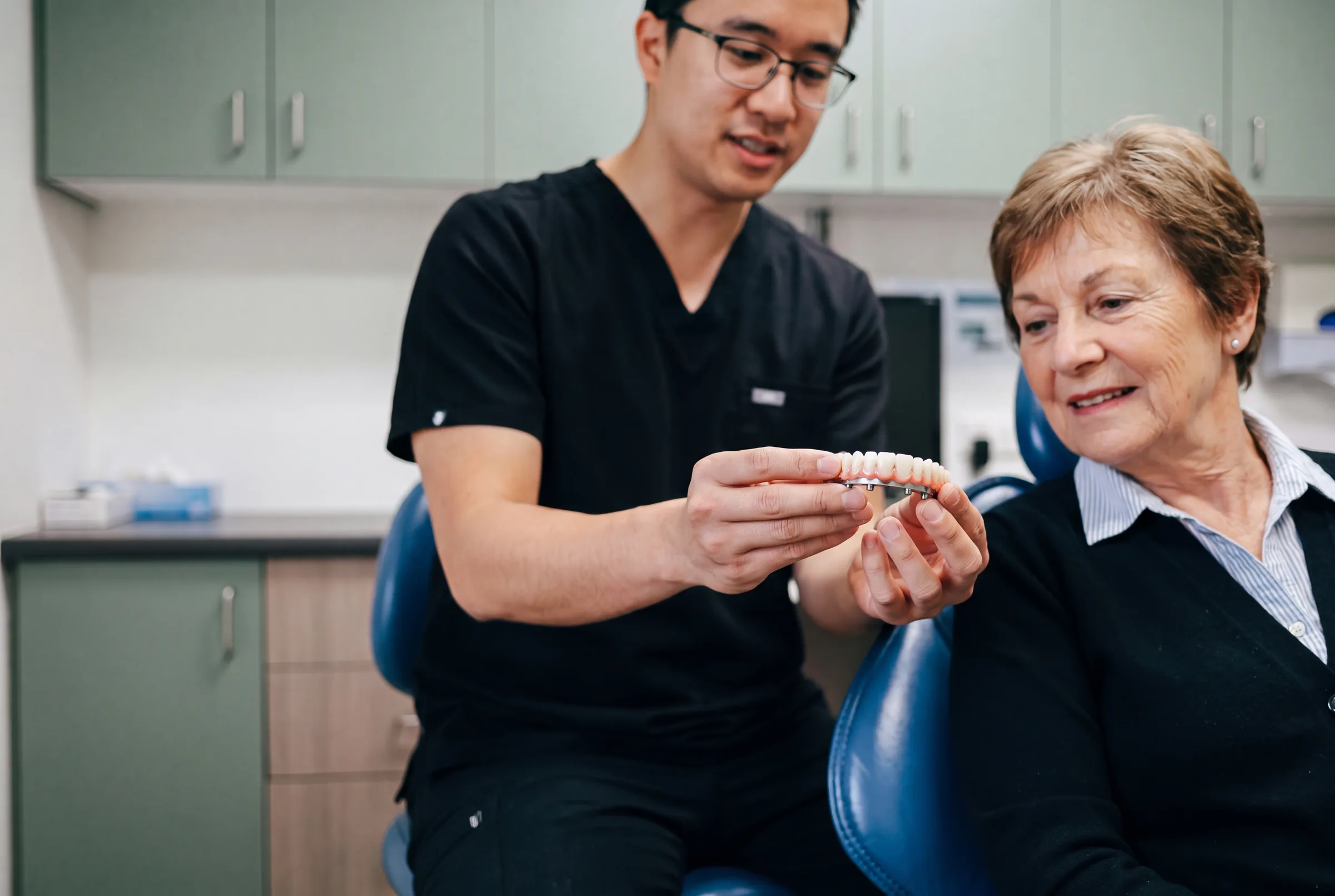 A patient discussing a full-arch implant plan and written quote at Enhanced Dental Studios.