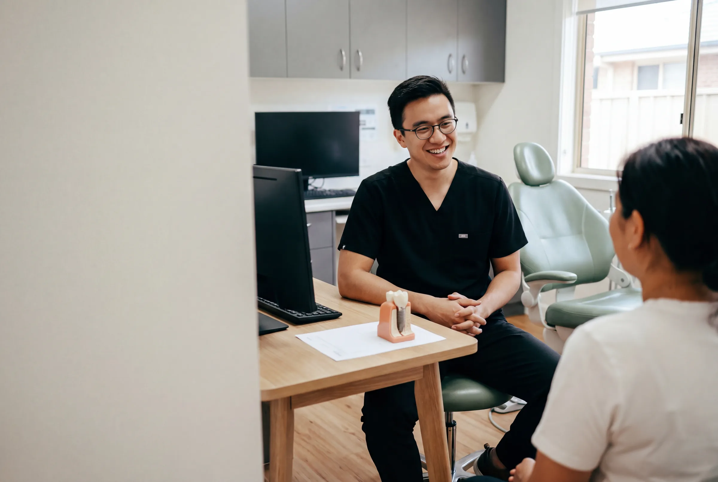 A dentist talking a patient through an itemised dental implant quote at Enhanced Dental Studios.