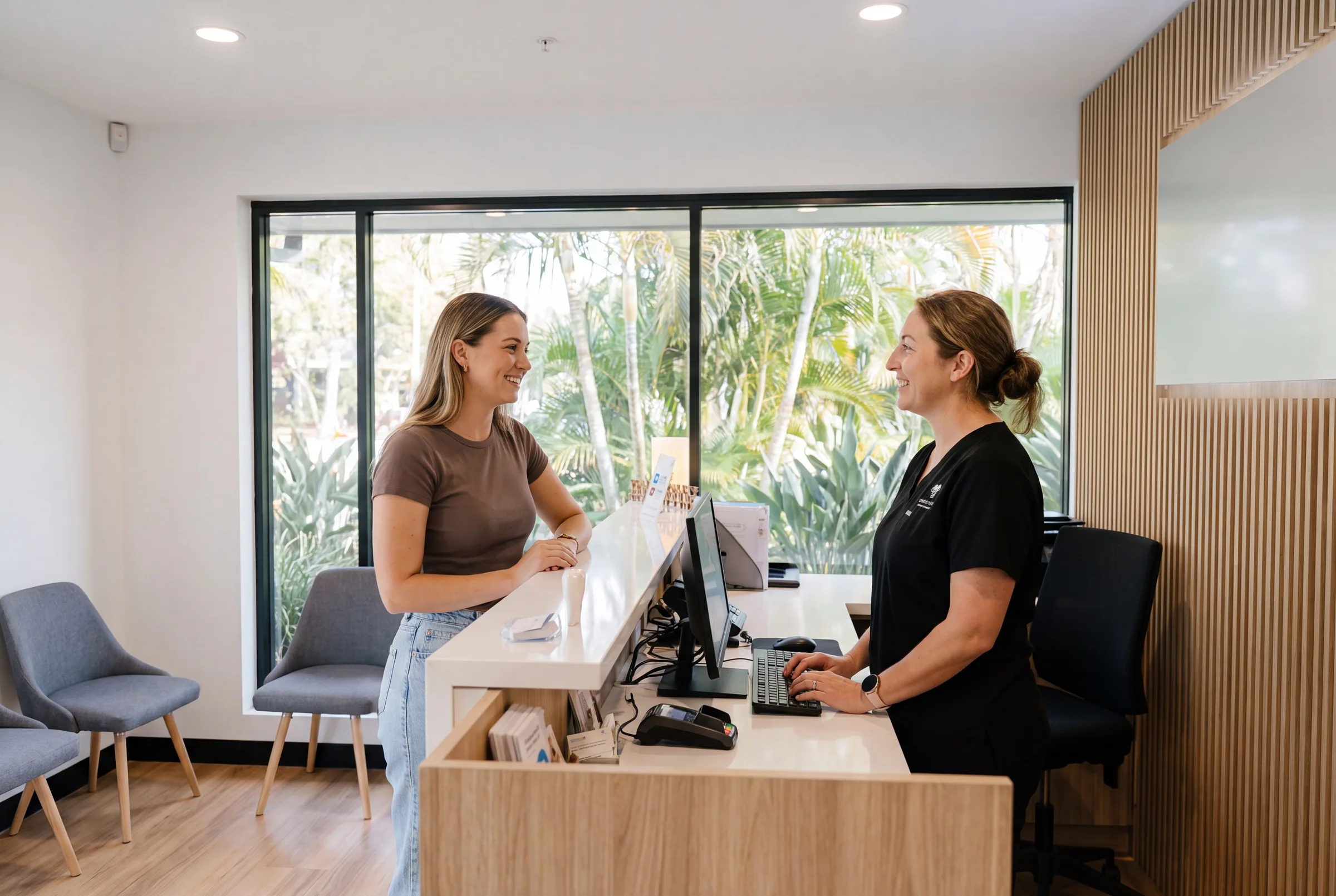 An Enhanced Dental Studios patient checking in at the front desk with friendly reception staff.