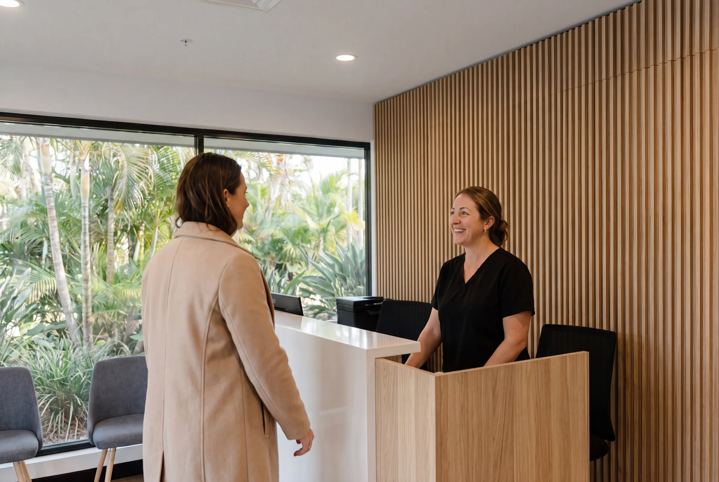 A new patient being welcomed at the Enhanced Dental Studios front desk.