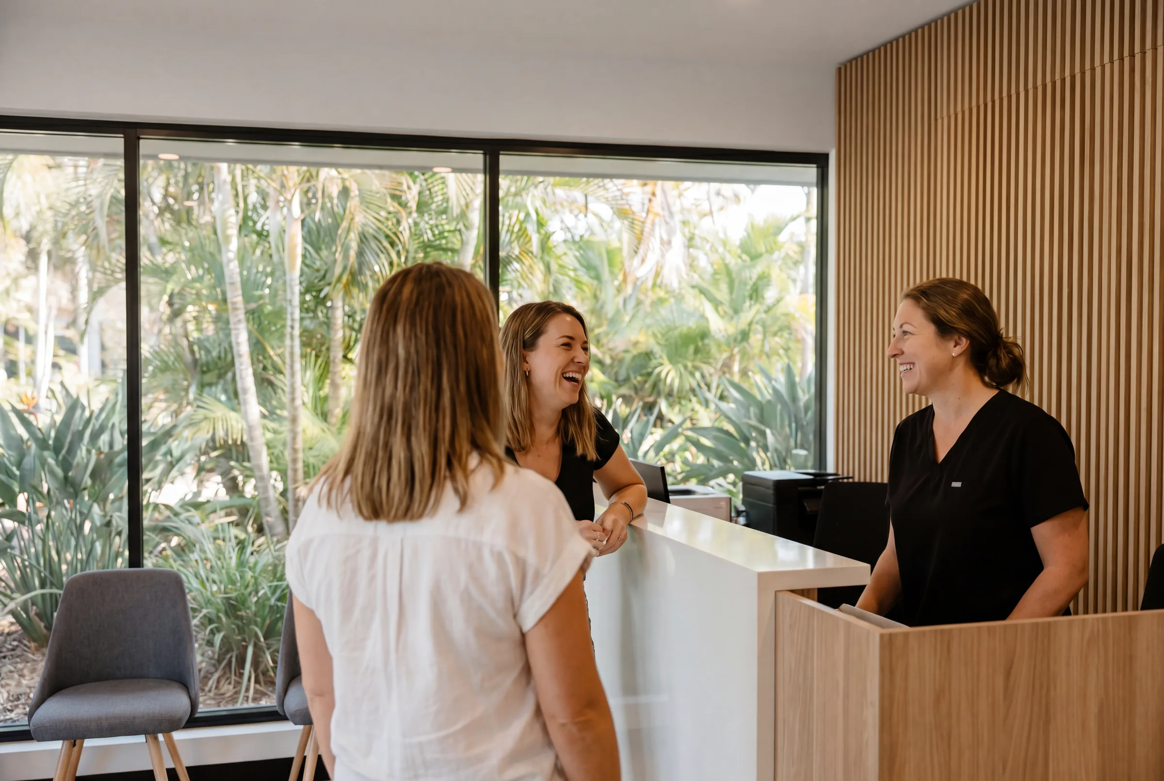 A happy Enhanced Dental Studios patient admiring her smile in a mirror with her dentist.