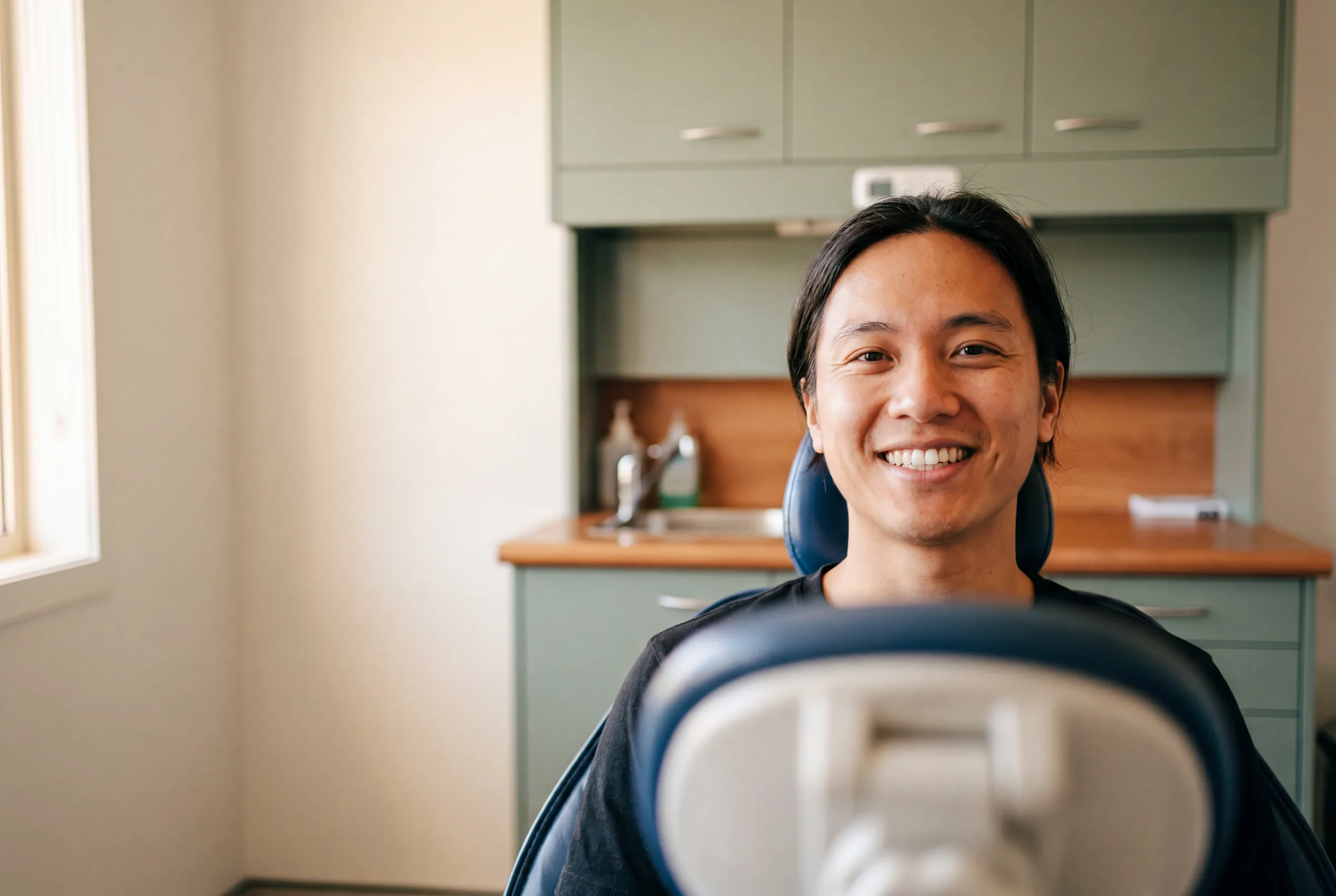 An Enhanced Dental Studios dentist matching a tooth shade with a smiling patient.