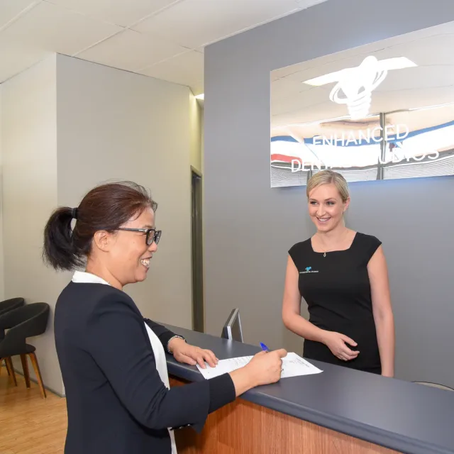 A patient signing in at the Enhanced Dental Studios front desk.