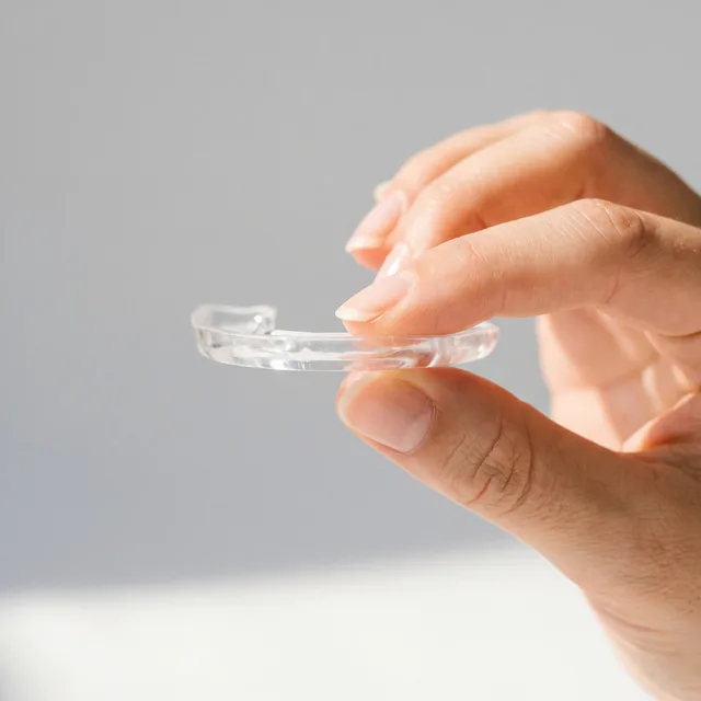 A slim, clear custom appliance made at Enhanced Dental Studios.
