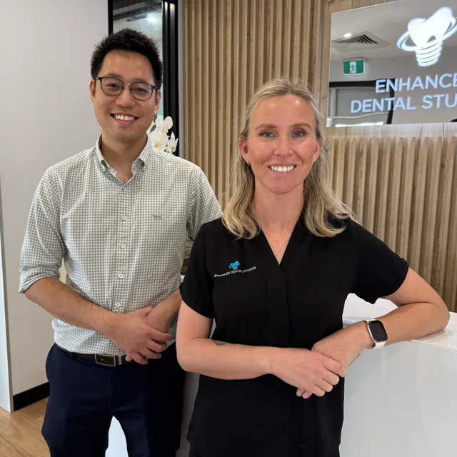 Two friendly Enhanced Dental Studios team members at the reception desk.