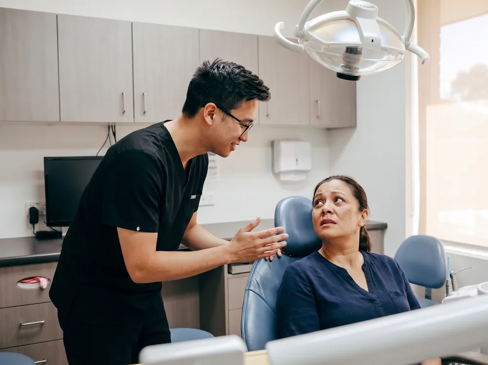 An Enhanced Dental Studios clinician calmly reassuring a patient who has just arrived in pain.