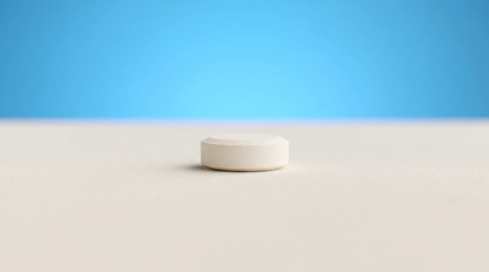 One small round white mint lying alone on a plain surface in a wide empty frame