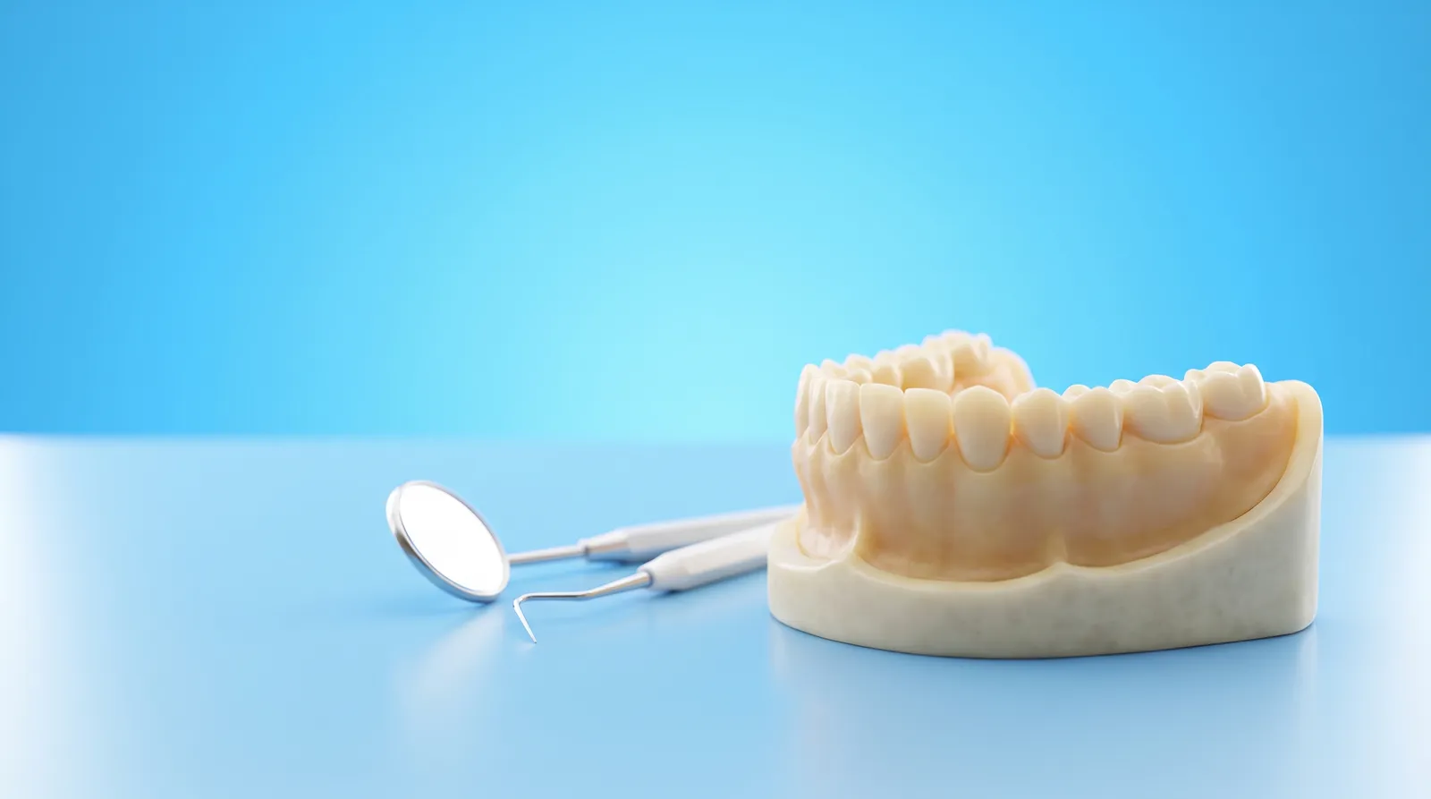 A dental arch model beside a small mirror and probe, laid out ready