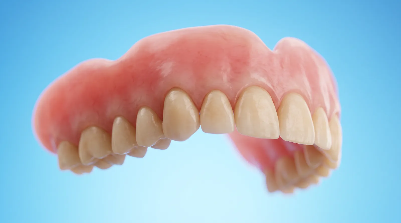 A freshly made full denture with a smooth pink base, seen from a low angle