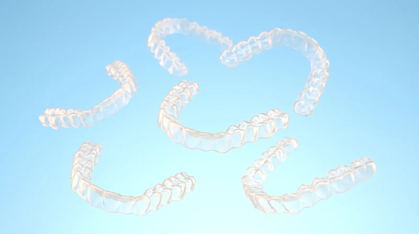 Five identical clear aligner trays floating apart from one another