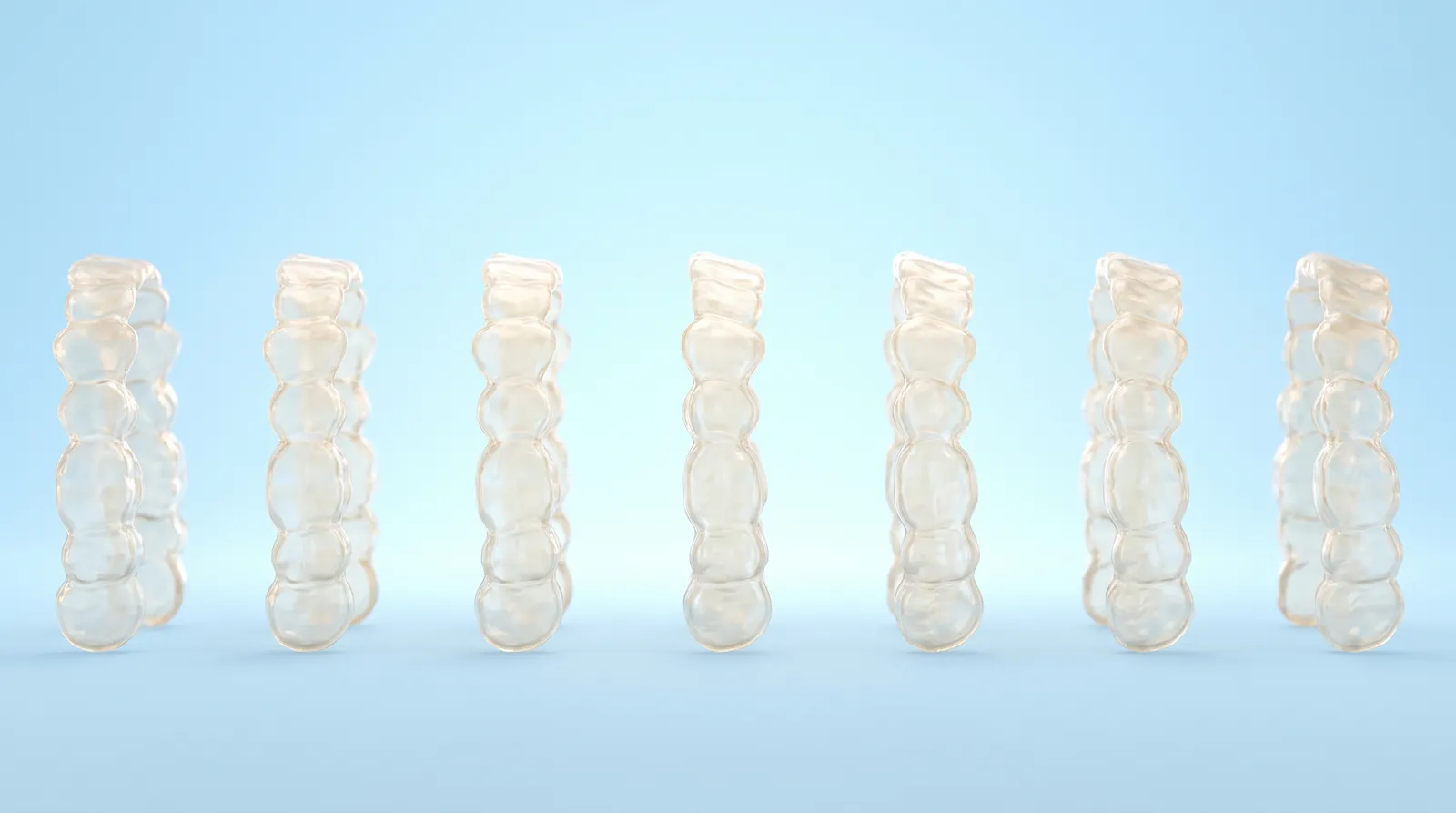 Seven clear aligner trays standing upright in a neat, evenly spaced row