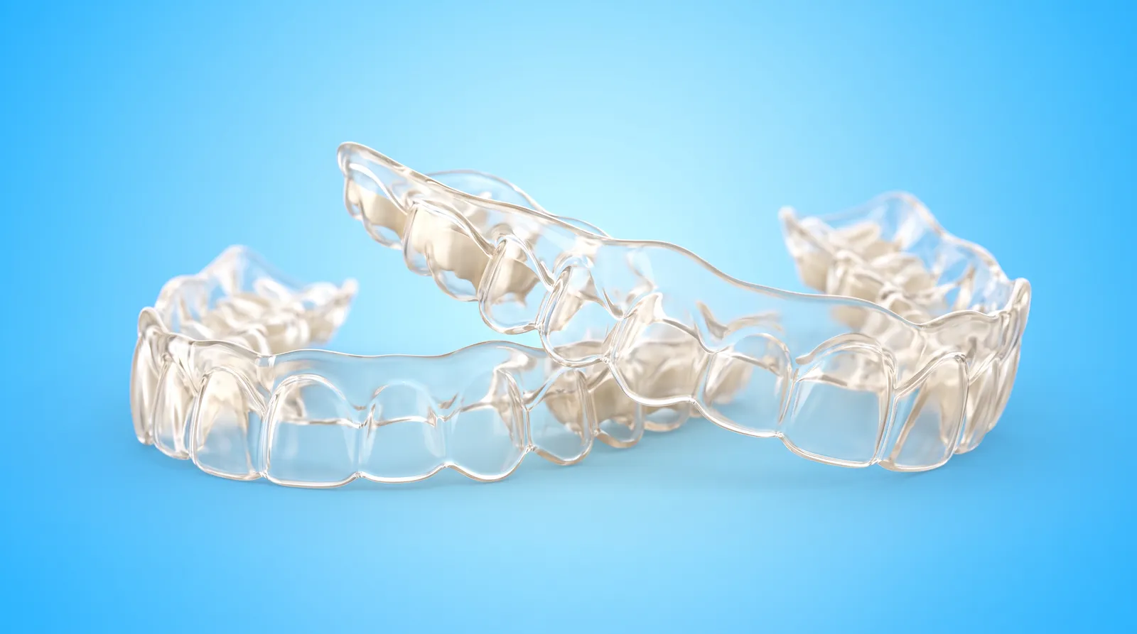 A pair of custom-made clear whitening trays resting together, made to fit one mouth